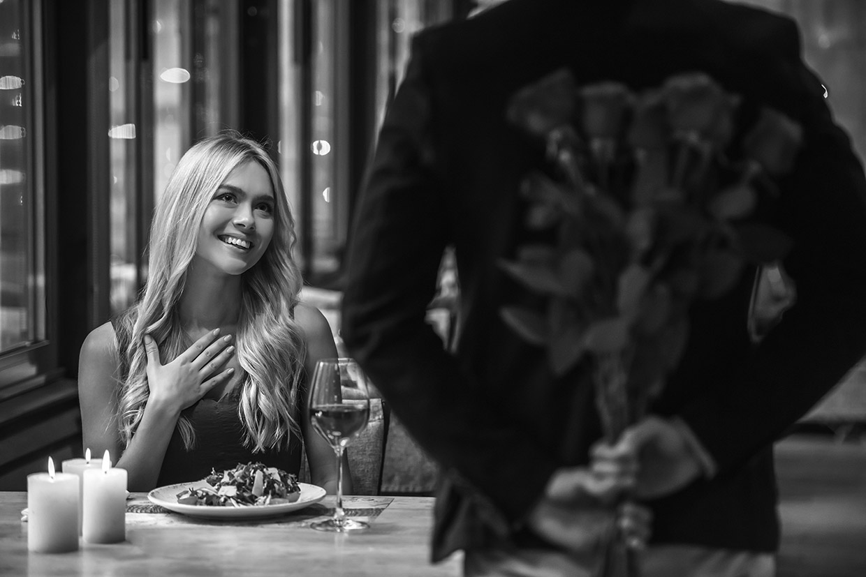 Man surprises woman having dinner with roses